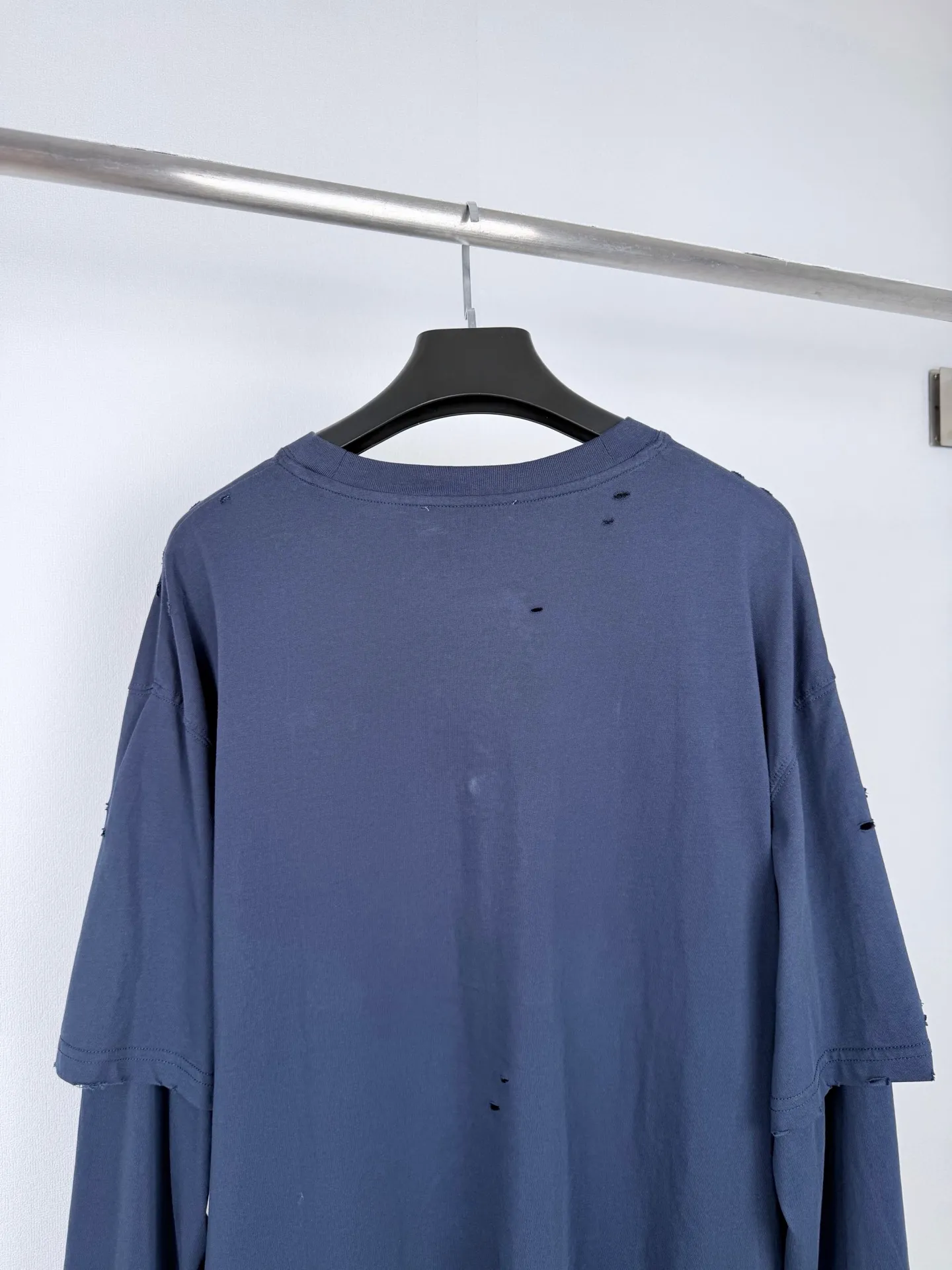 Acne Studios fake two-piece long-sleeved T-shirt with distressed logo. Customized Arashi weft-order plain cotton. Delicate and soft, warm and skin-friendly. Indigo-green covering the body. Matt low-saturation tones. Spreading the unique cool and relaxed charm of Retro deconstruction. The neat round neck is simple and restrained. The layered structure skillfully creates fake two-piece layers. The three-dimensional look of short sleeves stacked on long sleeves is naturally revealed in silence. The chest is embellished with the seasonal denim-style rivet logo. The Retro imprint is dimly deposited on the fabric. The body is staggered with frayed holes and stretches casually. The original texture of the deconstructed fabric. The loose shoulder silhouette is relaxed and relaxed. The cool and deconstructed Nordic aesthetics are integrated into daily clothing. The avant-garde quiet luxury style of alienation and restraint is demonstrated. Process 1: Using glue printing. The chest printing has been revised three times with the film screen. Use glue liquid paint to print the pattern on the fabric. Bake the fabric to fix the printing pattern. Process 2: Many parts of the body of the garment are worn by pure artificial regular positioning and manual brushing to add texture and depth to the surface of the garment to imitate the texture of natural wear and tear. Process 3: The fabrics are fermented and washed to give a better hand feel. Not easy to deform, not easy to shrink, not easy to fade, and maintain long-term beauty. Accessories: Customized 1:1 Acne trademark. Fit: Loose fit. Size: S M L XL